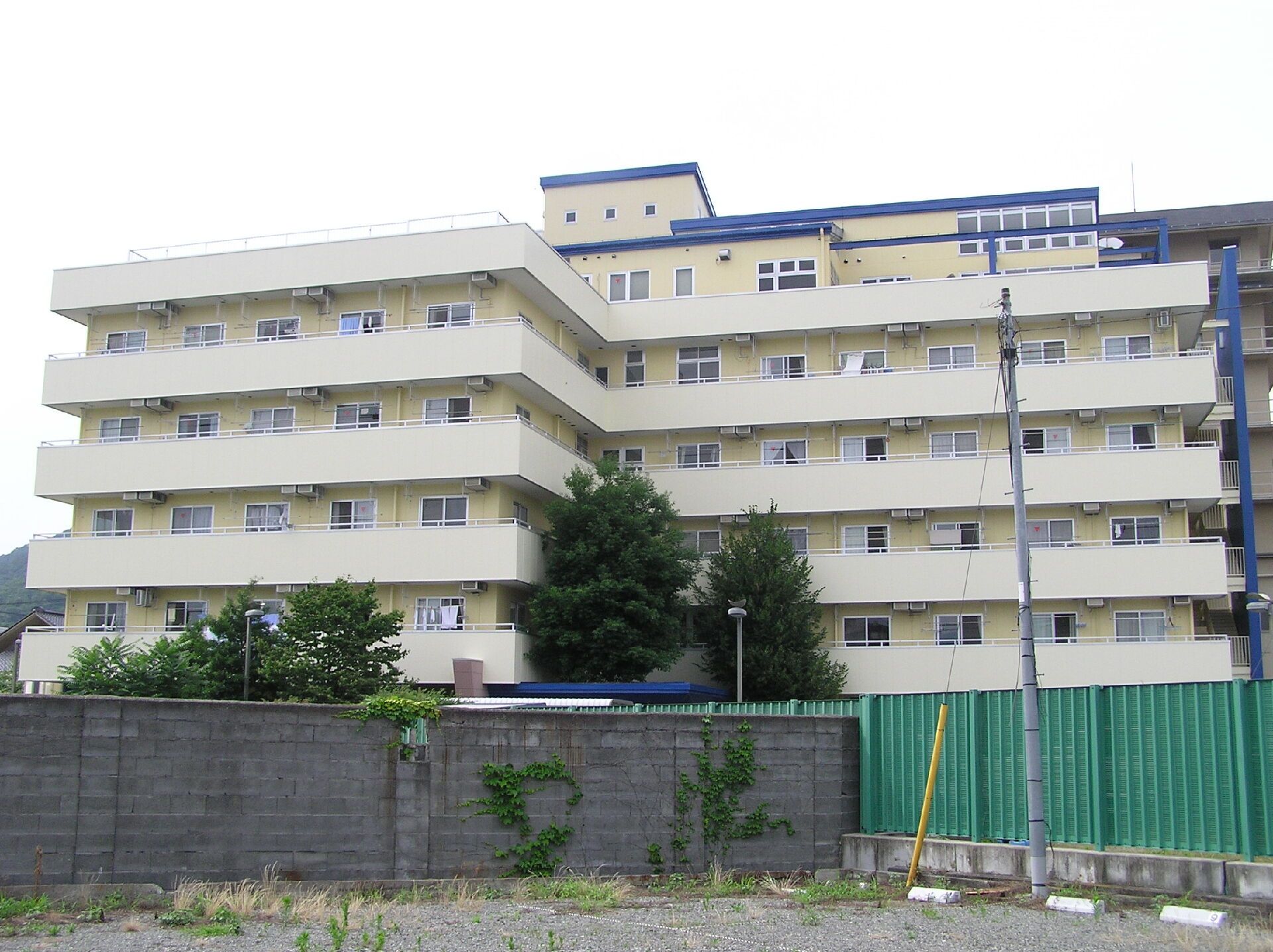 高齢者2名とスタッフが手を握りながら談笑している様子。施設内の会話の一画面