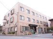 当施設は、茶色い3階建ての建物である。周りには、花や植物を植えている。すぐ目の前が駐車場となっている。