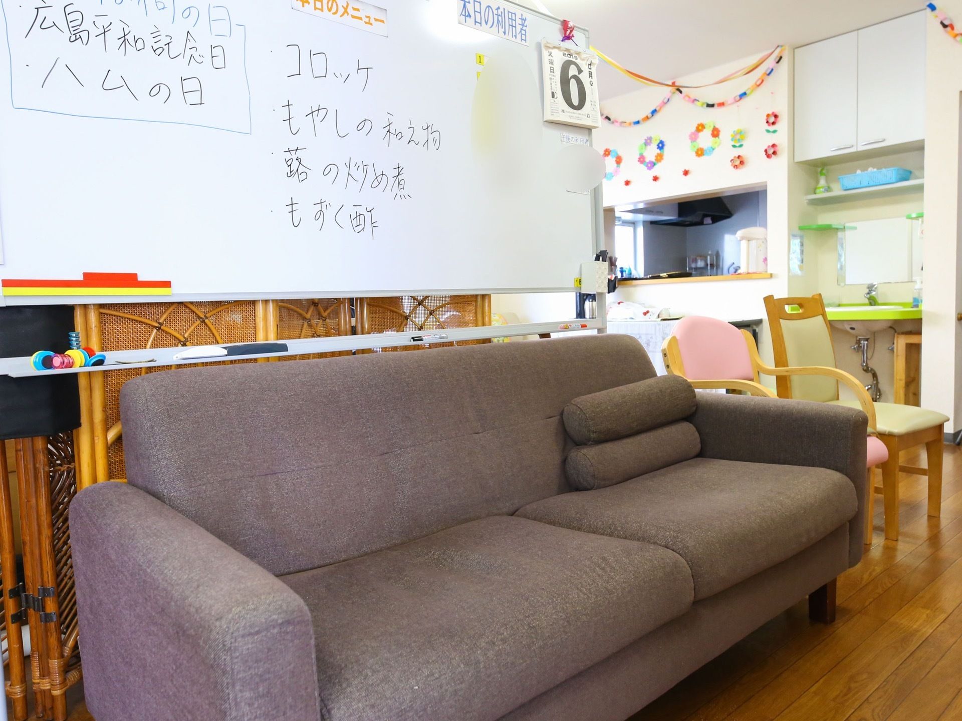 食堂前に設置されているソファーの後ろにホワイトボードが立てられている。献立やお知らせが記載されている。