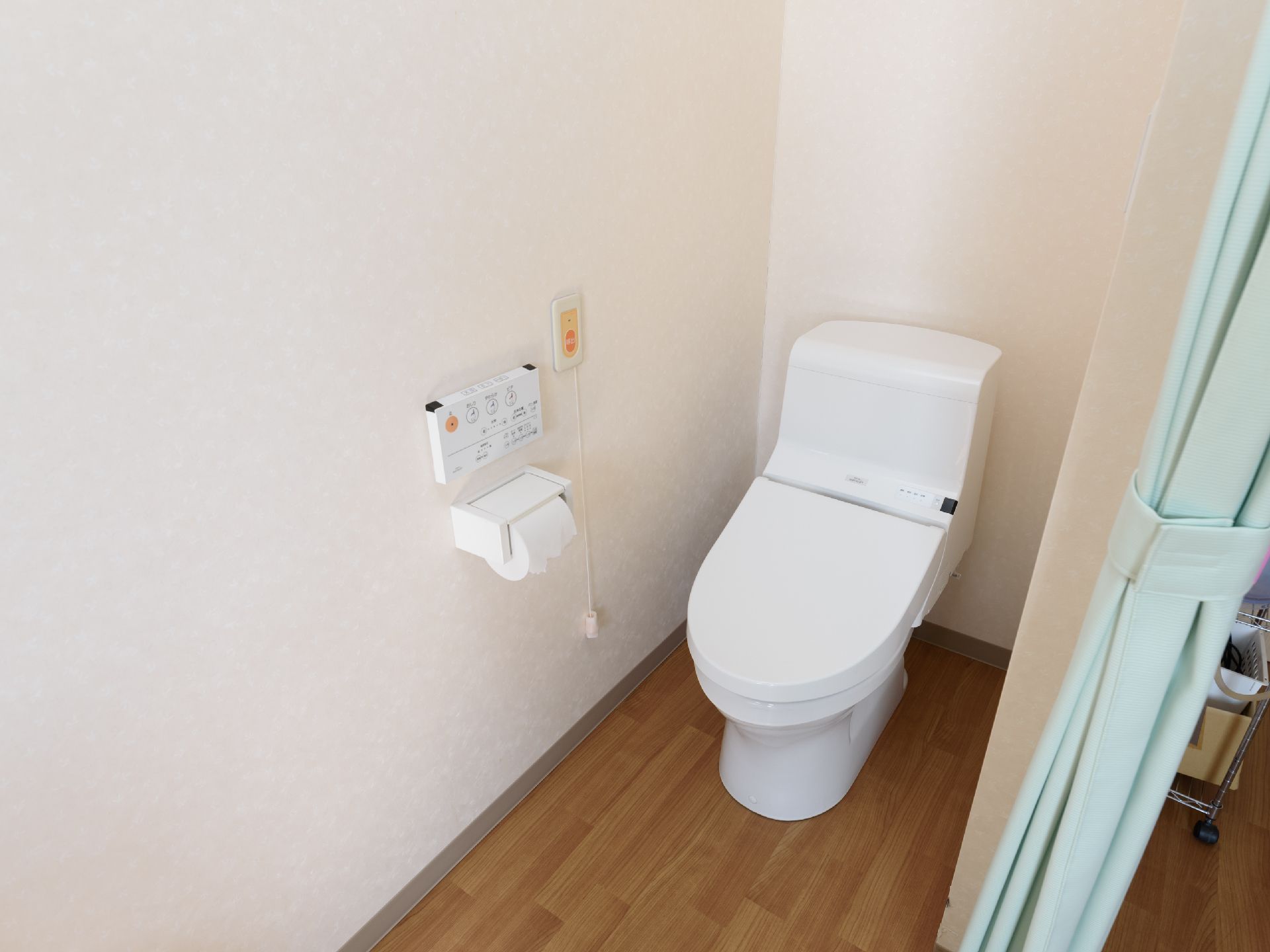 ブルーのカーテンで区切られたトイレで、洋式便座が1台設置されている。壁にナースコールが。