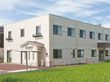２階建ての建物の周りには段差がなく駐車スペースもあり、周辺にも緑が多い。