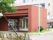屋根付きの車寄せが設けられているグループホームで、外壁はブラウンを基調とした落ち着いた色合いとなっている。