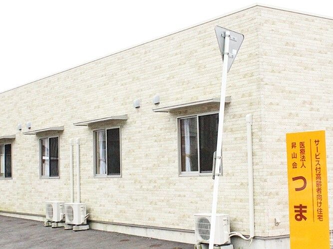 アイボリー色のレンガ調の外壁で平屋建て。建物の前には住宅名が書かれた館銘板もある。