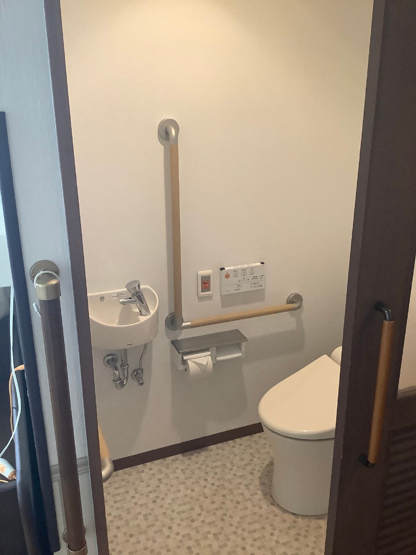 エル字型の手すりが付いているトイレは広く、ドアは引き戸で開け閉めがしやすい。