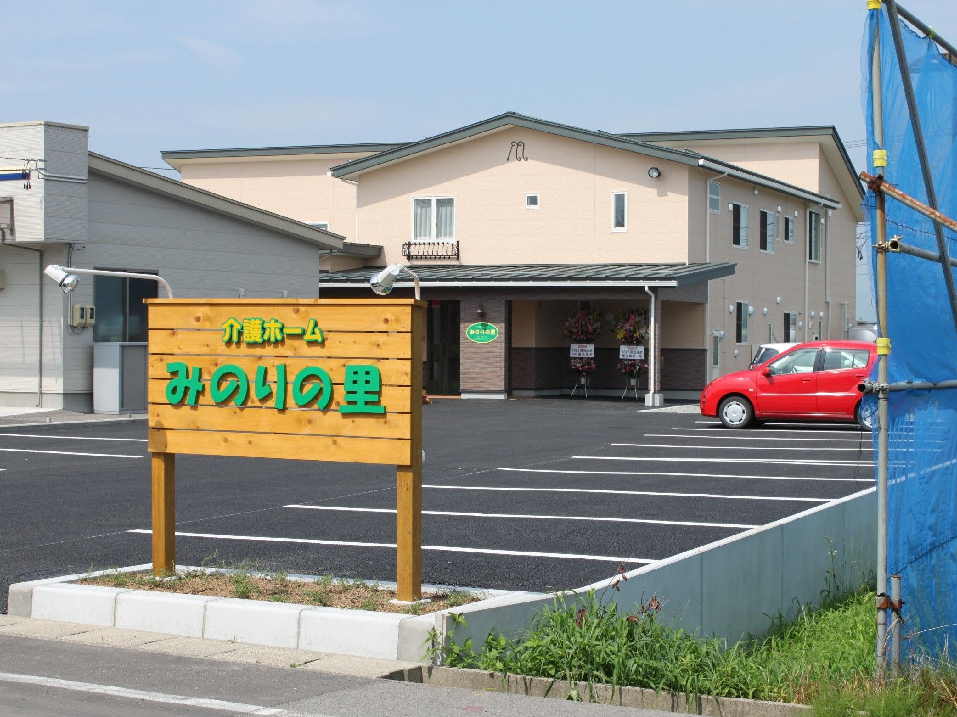 奥のほうに駐車場と建物、手前にみのりの里の看板がある場所