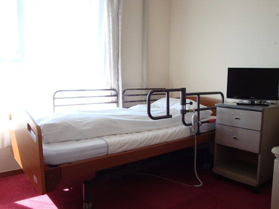 介護ベッドが置かれた居室には大きな窓が付き、カーテンが付けられている。