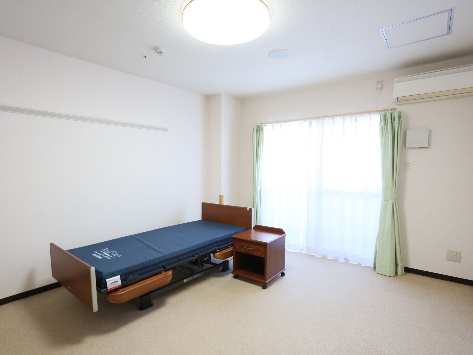 白を基調とした個室にベッドが置かれている。大きな窓からは日の光が差し込んでいる。照明とエアコンが完備されている。