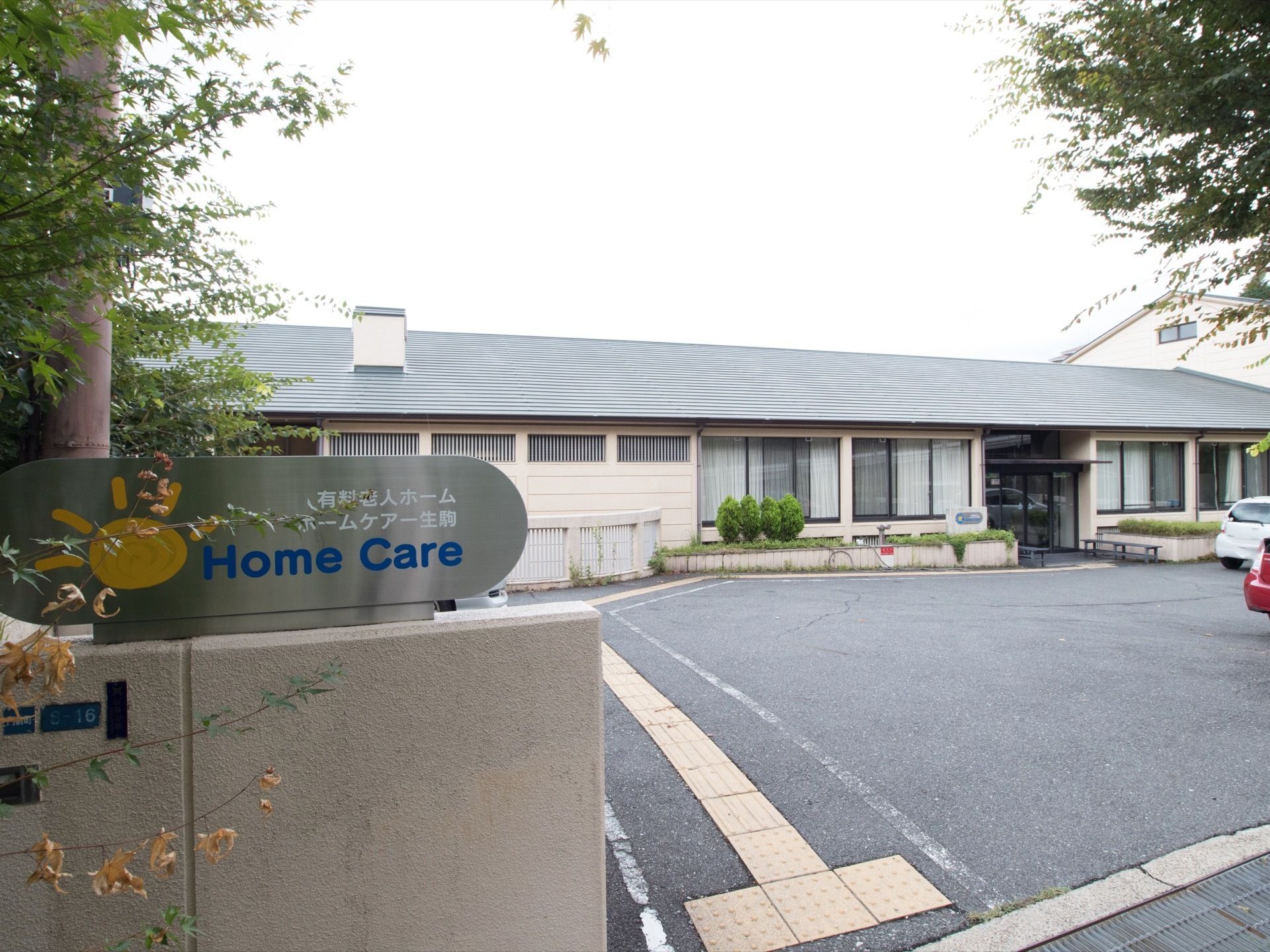 施設名が書かれた表札が門に設置されている。施設入り口近くは生垣が設けれられており、さまざまな植物が植えられている。