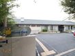 施設名が書かれた表札が門に設置されている。施設入り口近くは生垣が設けれられており、さまざまな植物が植えられている。
