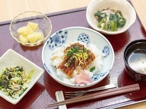 うな丼に野菜の小鉢、フルーツに汁物といった内容の食事。