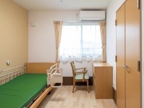 フローリングのシンプルな居室にはカーテンや収納、ベッド、デスクセットが付いている。