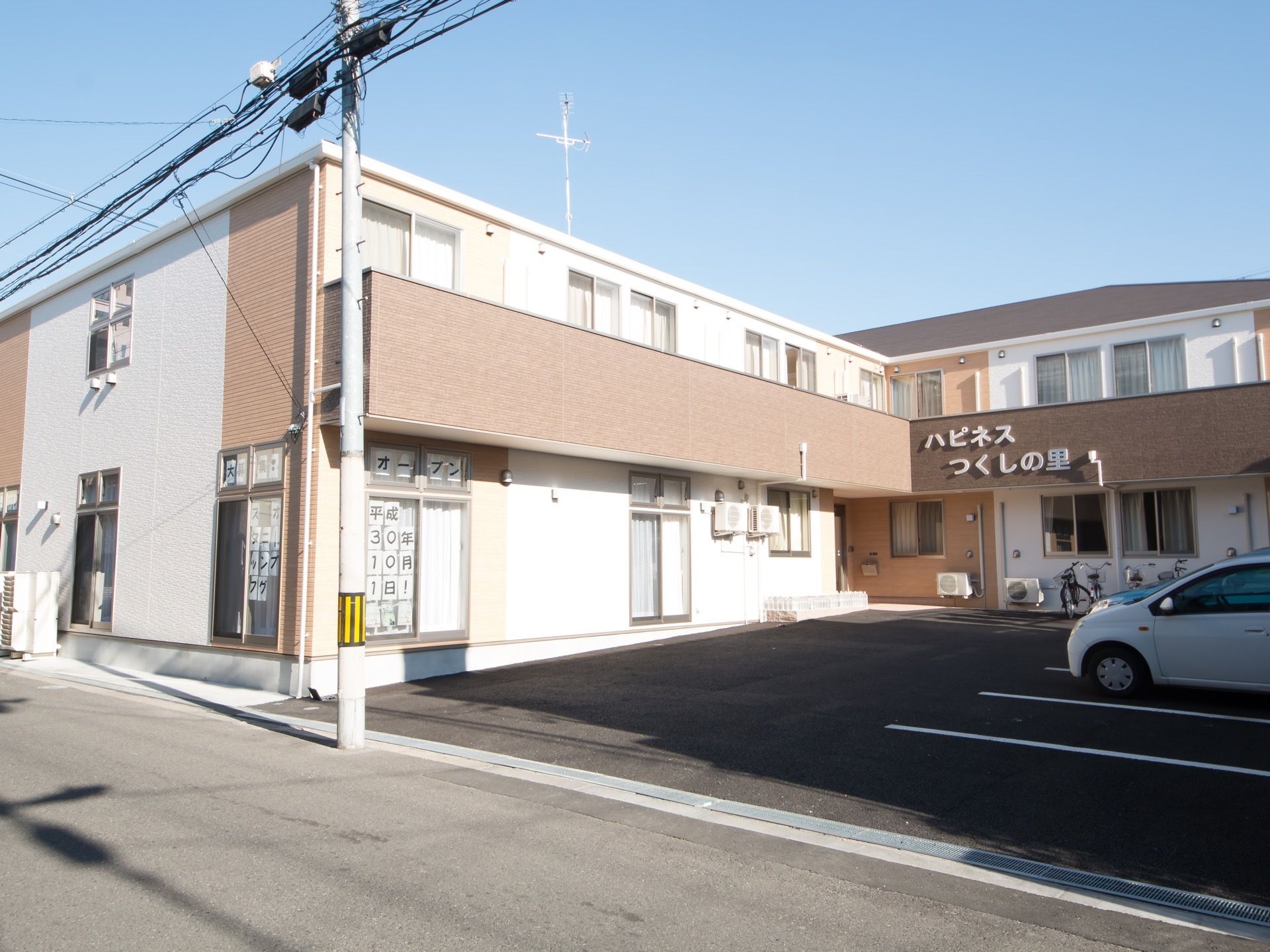 道路に面した位置にある、二階建ての建物。手前は舗装された駐車場になっている。壁には大きく施設名が書かれている。