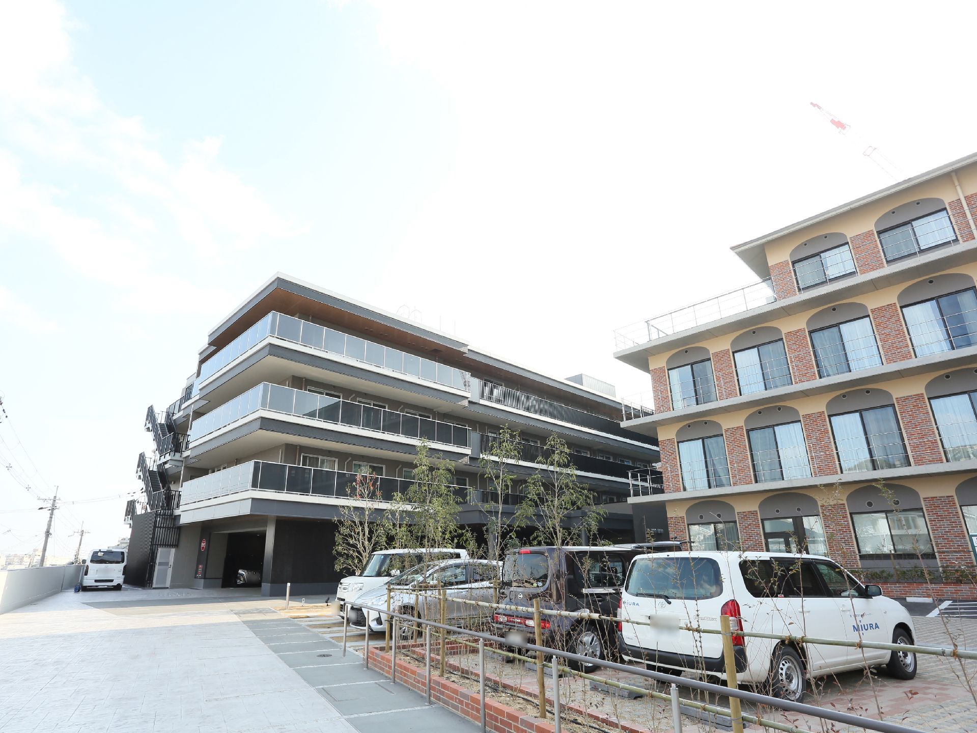 施設外へと続く道と駐車場の間には木々が植えられている。またその木々の近くには手すりが設置されている。