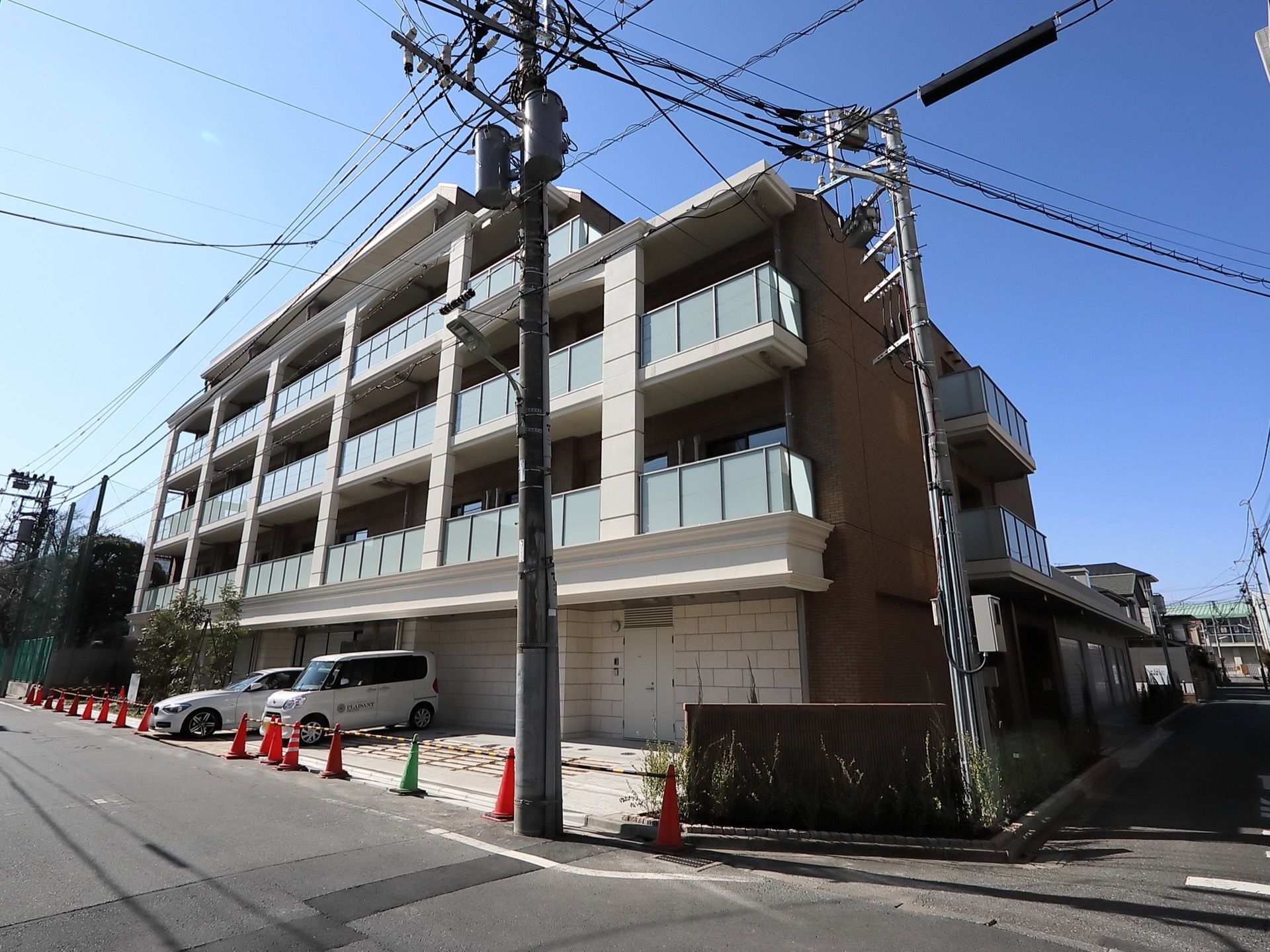 施設はブラウン色の外壁になっている４階建ての建物である。車を駐車することができるスペースが完備されている。
