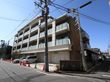 施設はブラウン色の外壁になっている４階建ての建物である。車を駐車することができるスペースが完備されている。