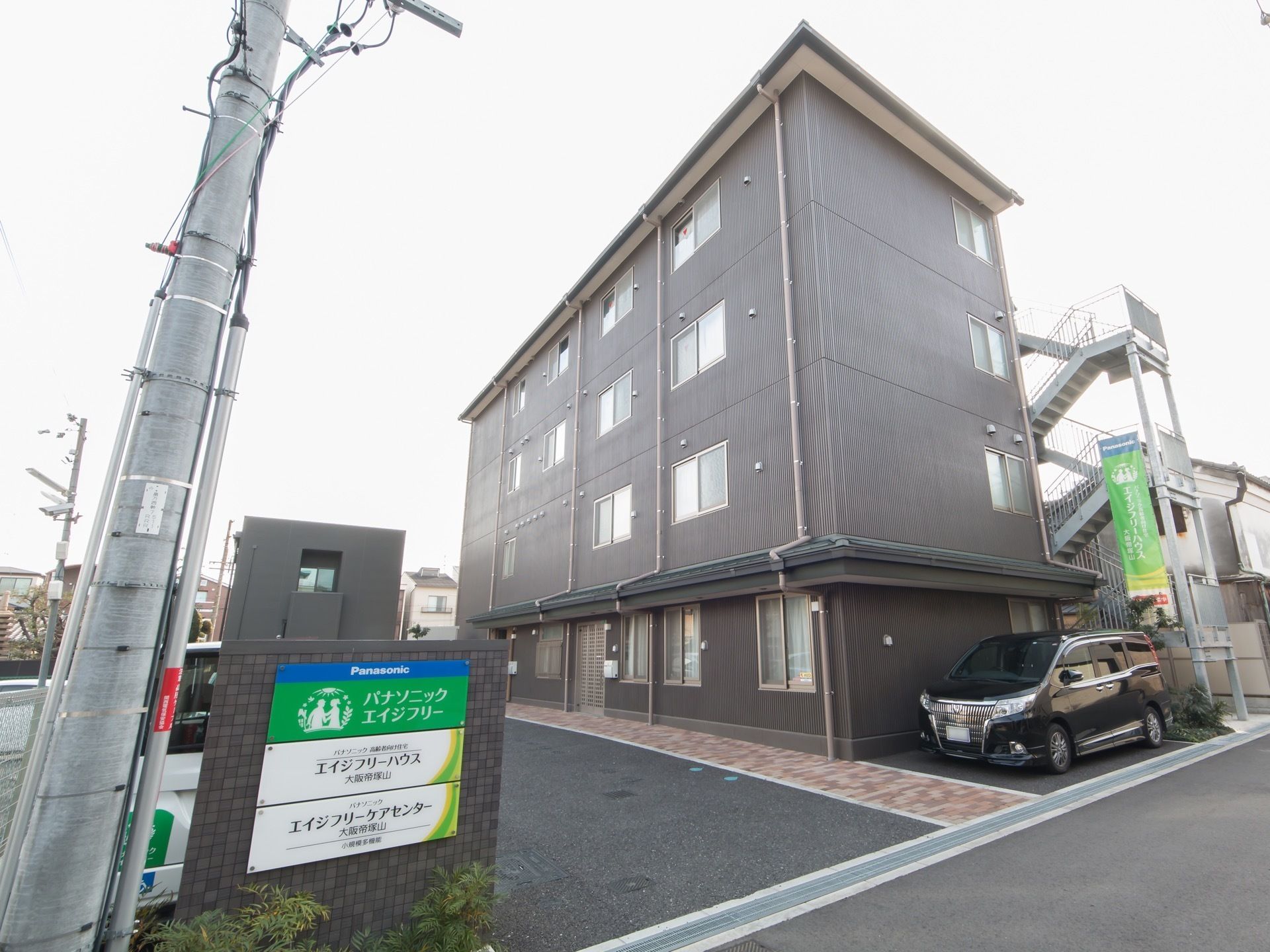 施設の敷地は広々としている。建物は４階建てになっており、ダークグレー色の外壁である。外階段が設置されている。