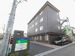 施設の敷地は広々としている。建物は４階建てになっており、ダークグレー色の外壁である。外階段が設置されている。