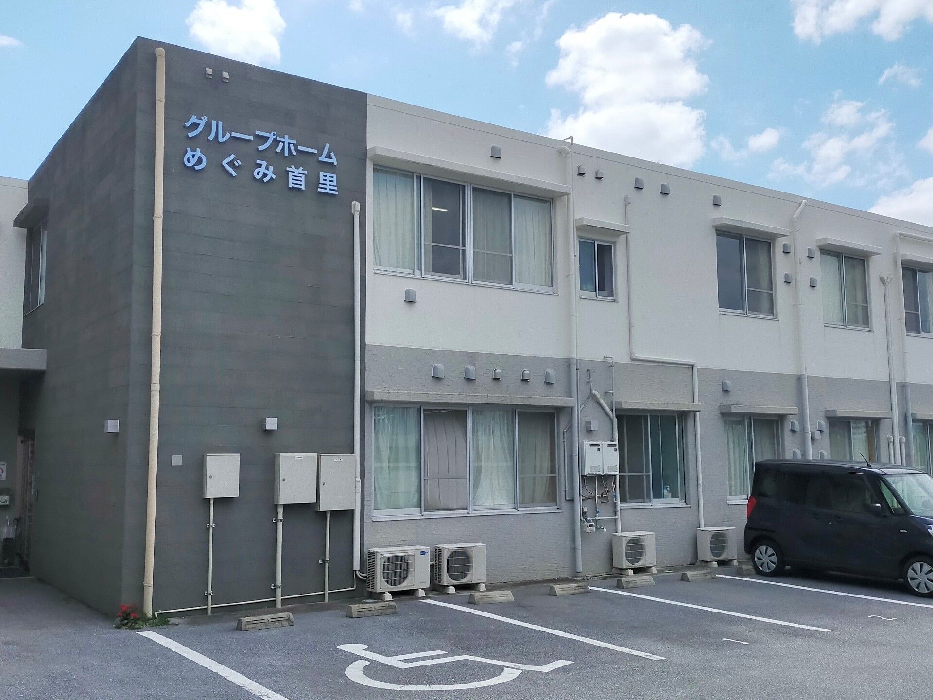車いすに乗っている女性とその人の手を握りながらこちらを向いて笑顔を見せるスタッフ