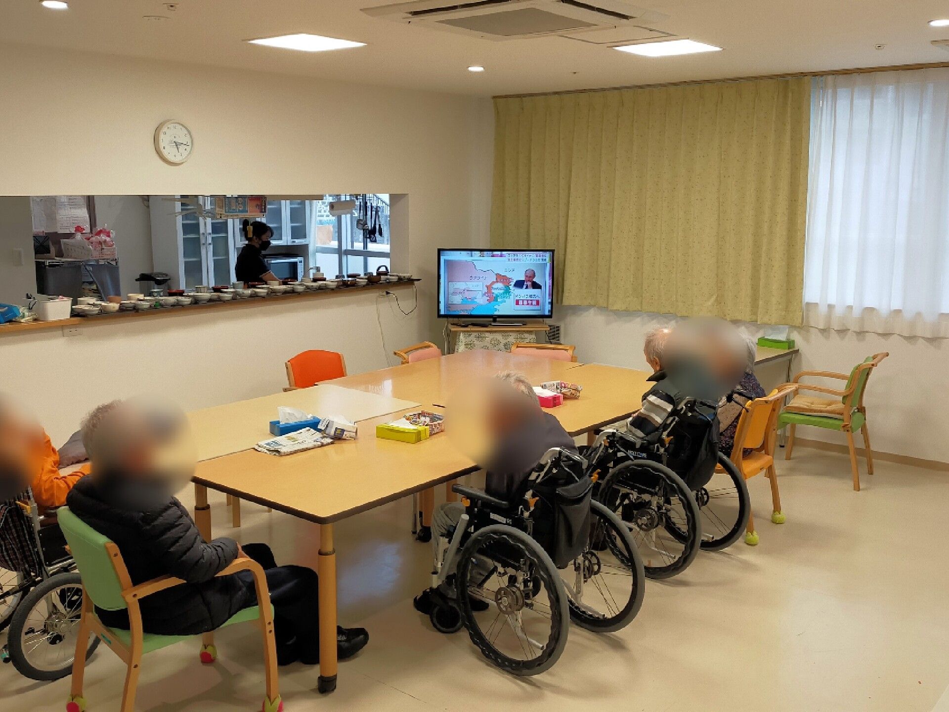車いすの女性と同じ視線で話している介護スタッフ。やわらかい表情で散歩している様子