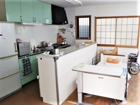 カメラ目線でほほ笑む男性。新聞を読みながらこちらを見ている様子。白いソファに座っている