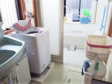 洗濯機が置いてある施設の水回り設備。奥のほうに浴室がある様子