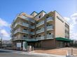 どっしりとしたベージュの7階建ての建物。各フロアにベランダが付き、外壁にはホーム名が書かれている。