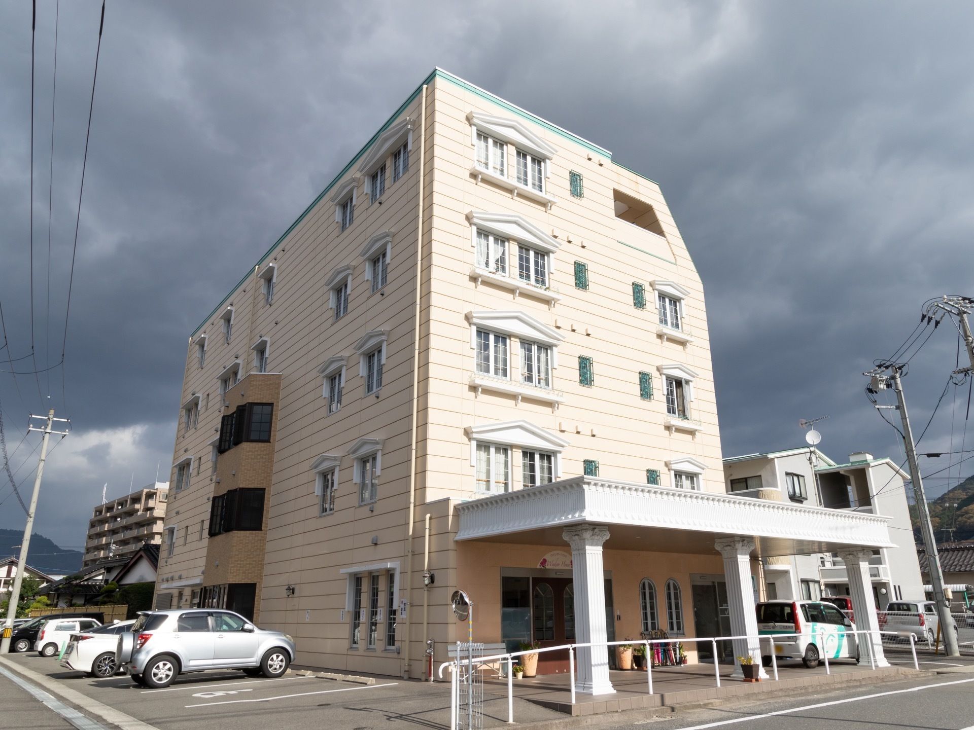 アイボリー系統の色の外壁を持つ５階建ての施設である。玄関前には、幅と奥行きのある白色の大きなひさしがある。