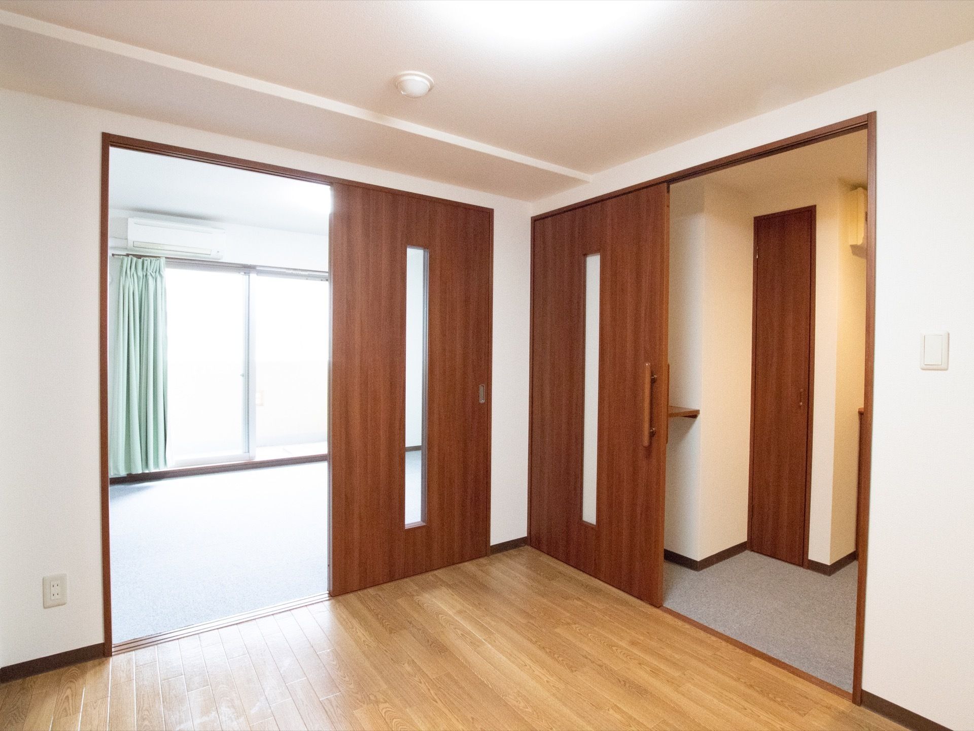 居室には、カーペット敷きとフローリングの部屋の2間がある。各間の仕切りは木目調のスライド式扉が設置されている。