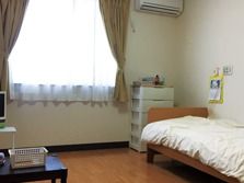 大きな窓があり明るい雰囲気。居室には、ベッドや収納ケースだけでなくエアコンもついている。