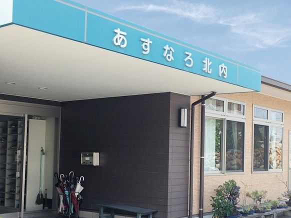 傘立てや掃除道具、ベンチが置かれた玄関。大きな屋根が付いている。