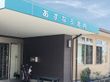傘立てや掃除道具、ベンチが置かれた玄関。大きな屋根が付いている。