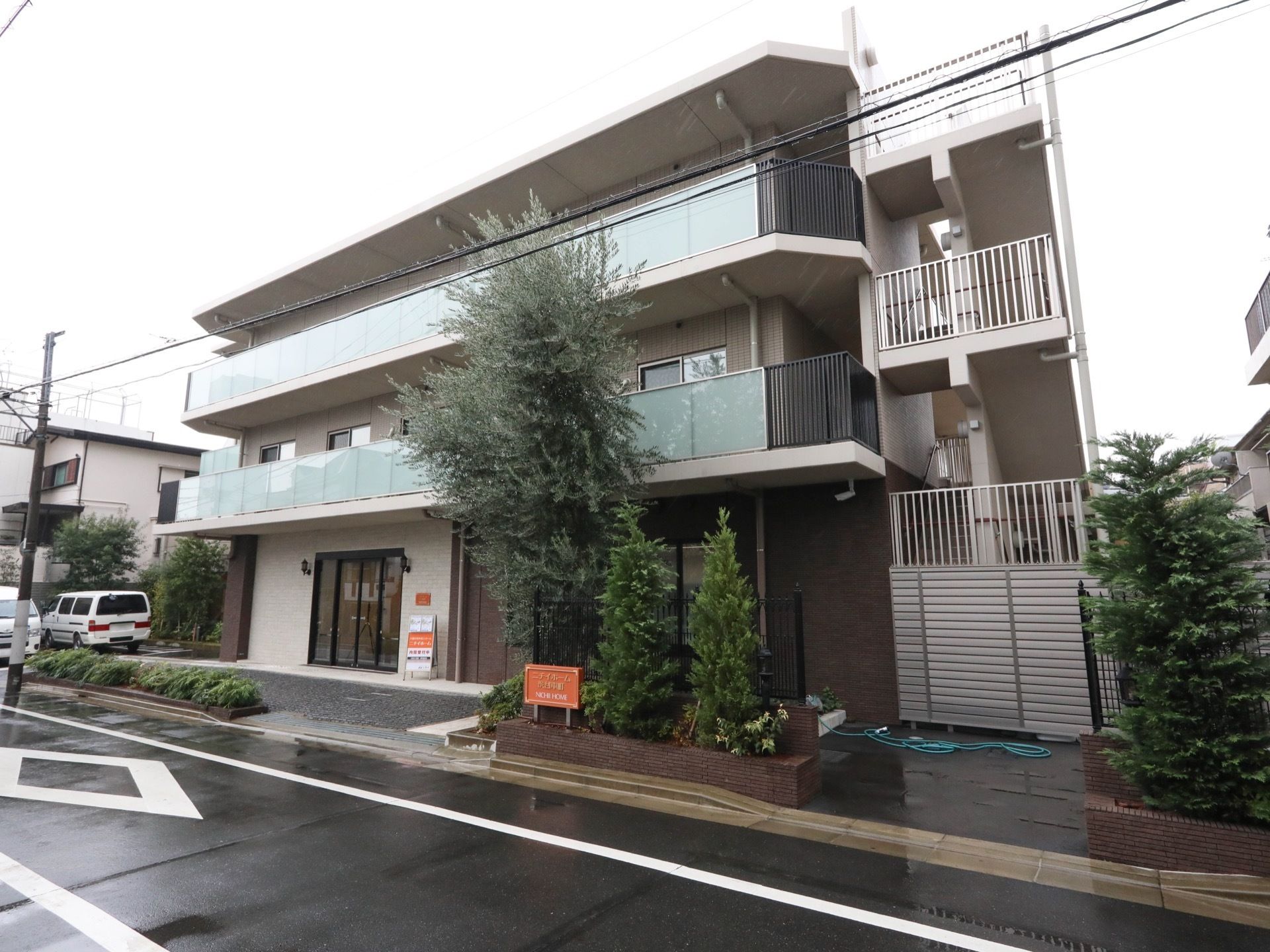 施設の外壁はブラウン色が基調となっており、３階建ての建物である。外階段があり、緊急時の避難経路が確保されている。