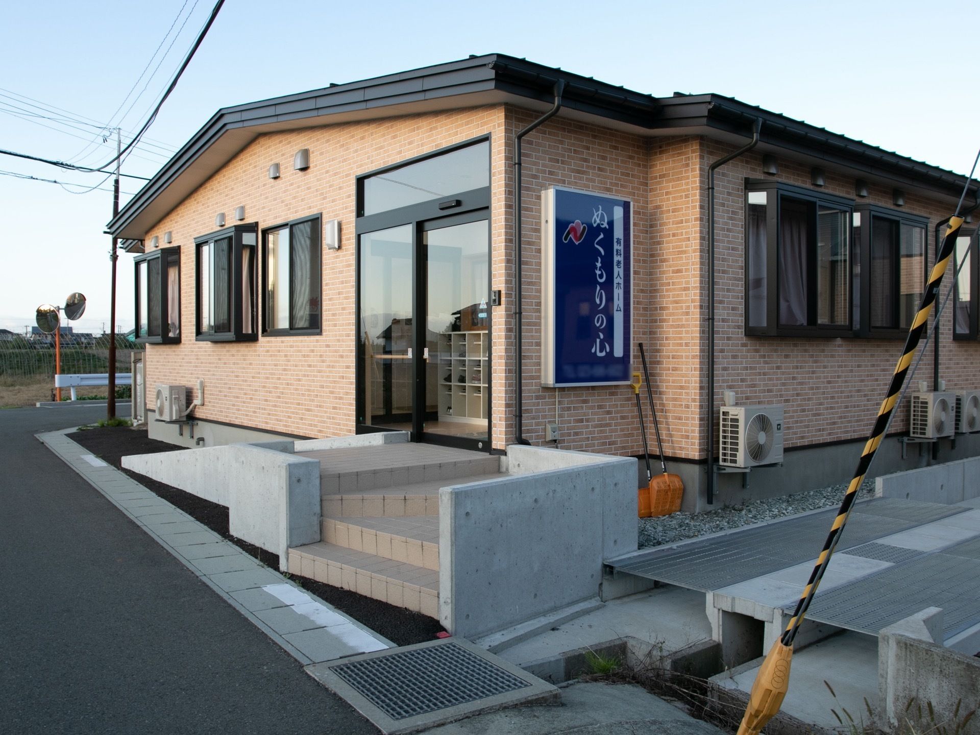 平屋建ての施設である。入口へは、両サイドにスロープと階段が分けて完備されている。外壁には施設看板が設置されている。