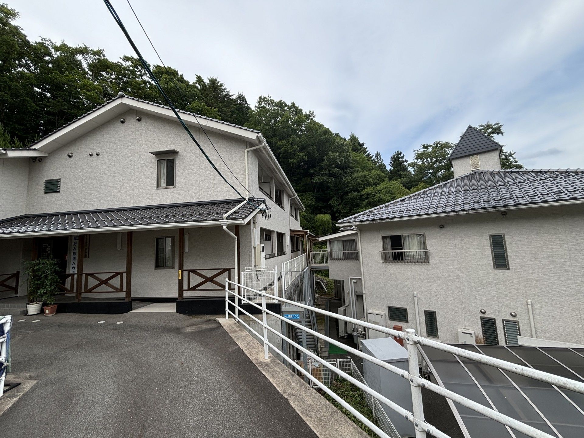 大きめの一軒家風の外観の施設。手前にエントランス部分が写っている