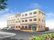 3階建ての建物はベージュ系で外壁には住宅名も書かれている。玄関には手すり付きのスロープが付いている。
