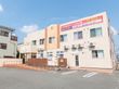アスファルトに隣接した２階建てでベージュの外観の建物