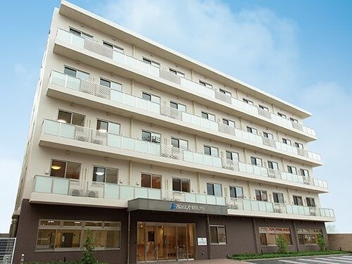 5階建ての建物は白とブラウンの外壁の大きな建物で、各フロアにベランダがある。