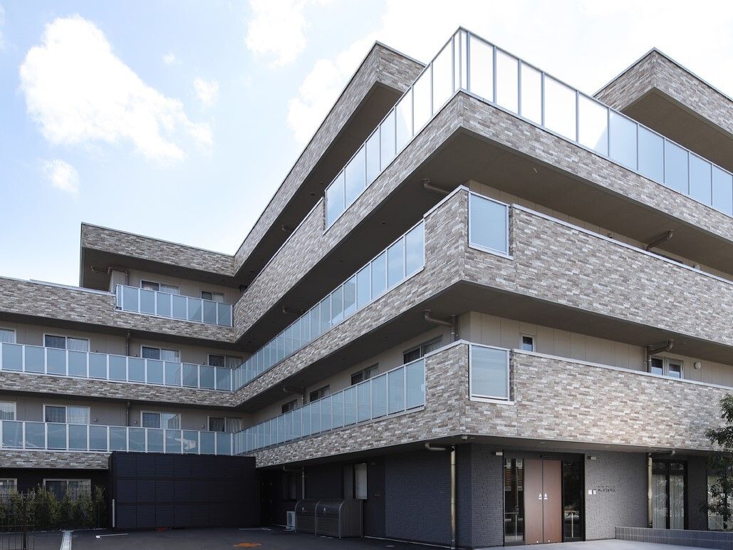 広いベランダが設置された茶色を基調としたシックなイメージの４階建ての施設