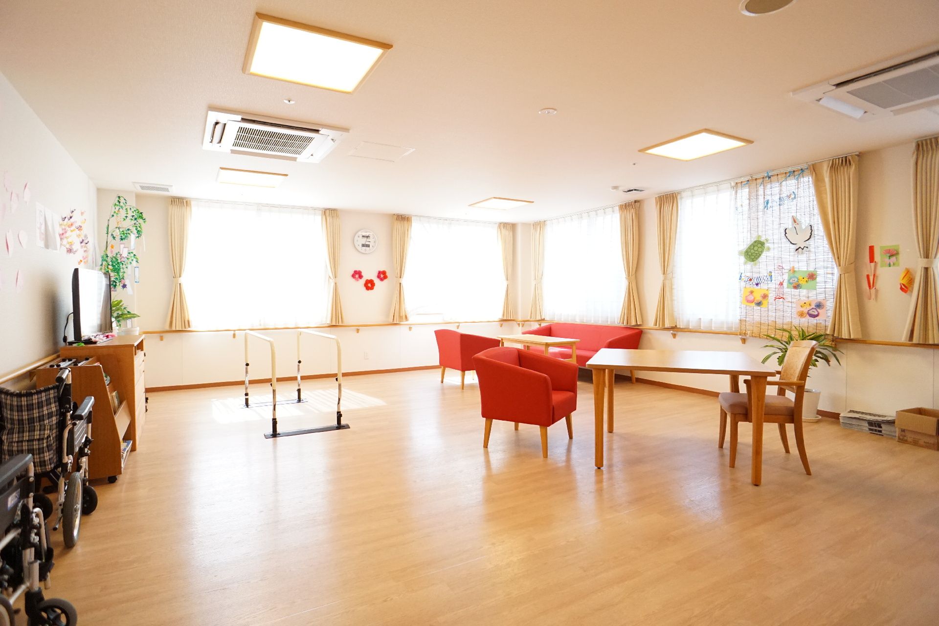 窓がたくさんある部屋に置かれた赤いソファーと平行棒