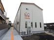 施設は公道に面している。隣地との間に、点字ブロックを敷いた通路が設置されている。建物の壁には、施設名称が入っている。