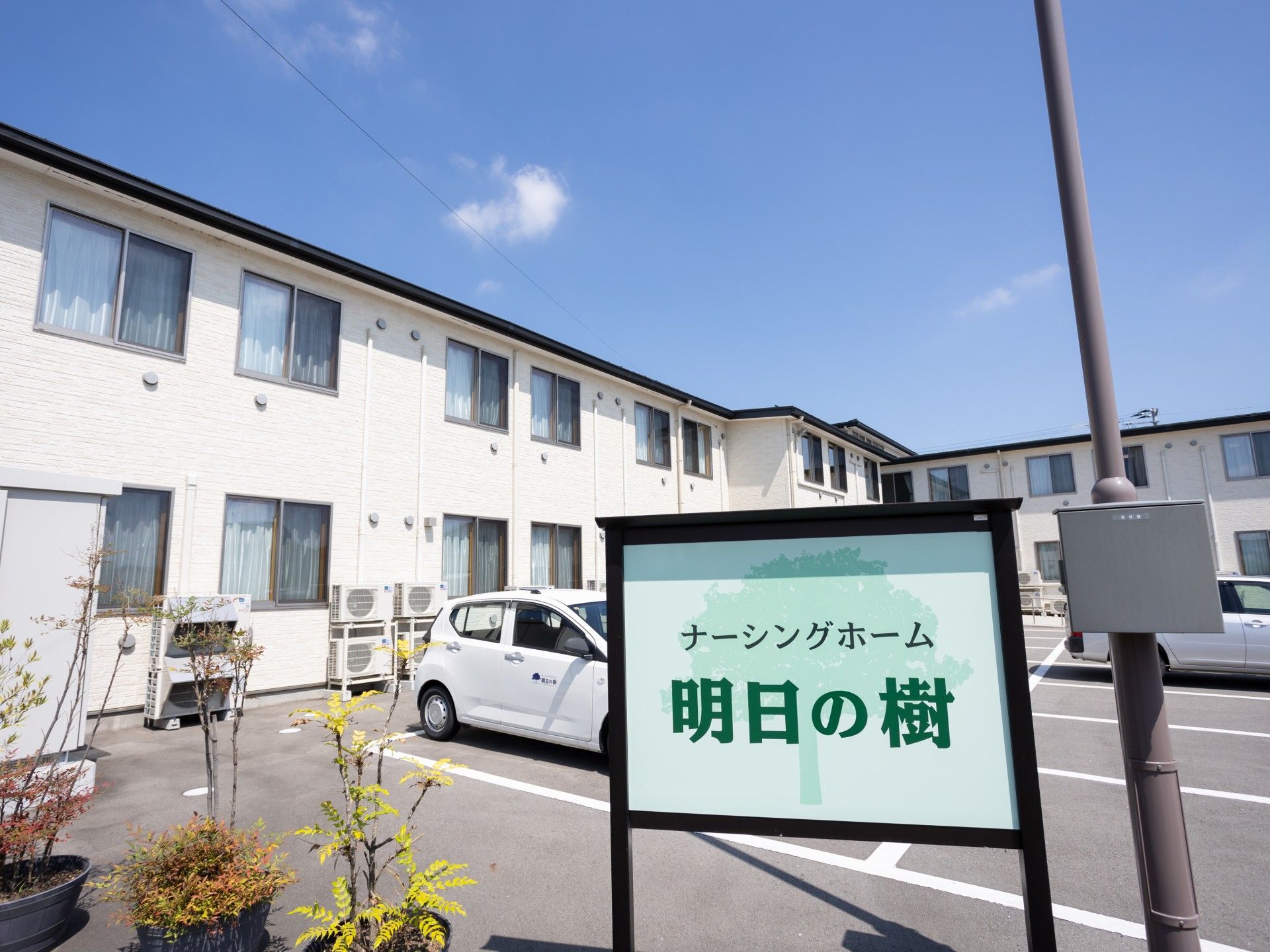 白い二階建て建物と看板