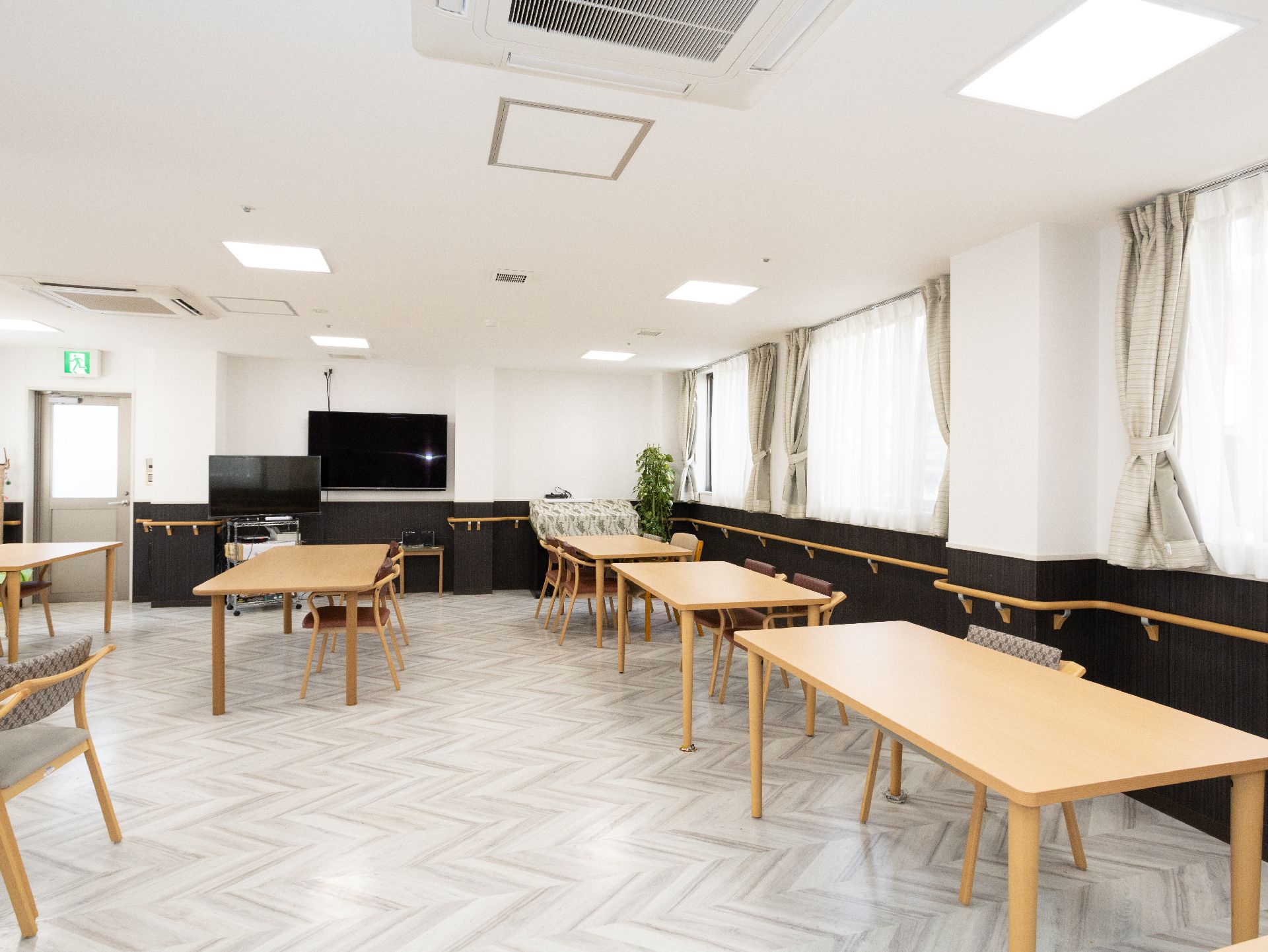 大きなテレビが設置され、テーブルが多数置かれているリビング