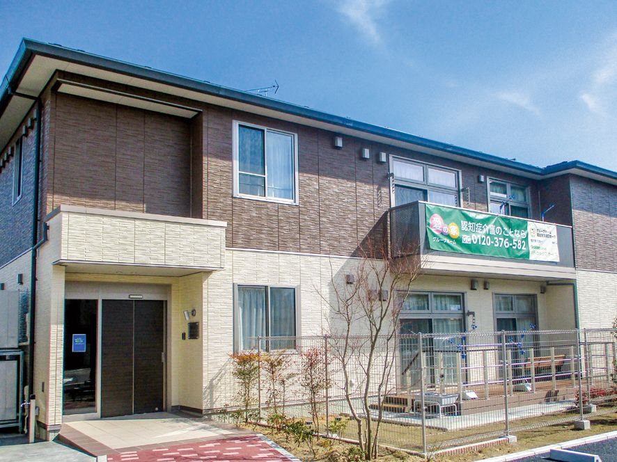 2階建ての建物。ブラウン系で2階部分にはベランダ、1階部分にはテラスがある。