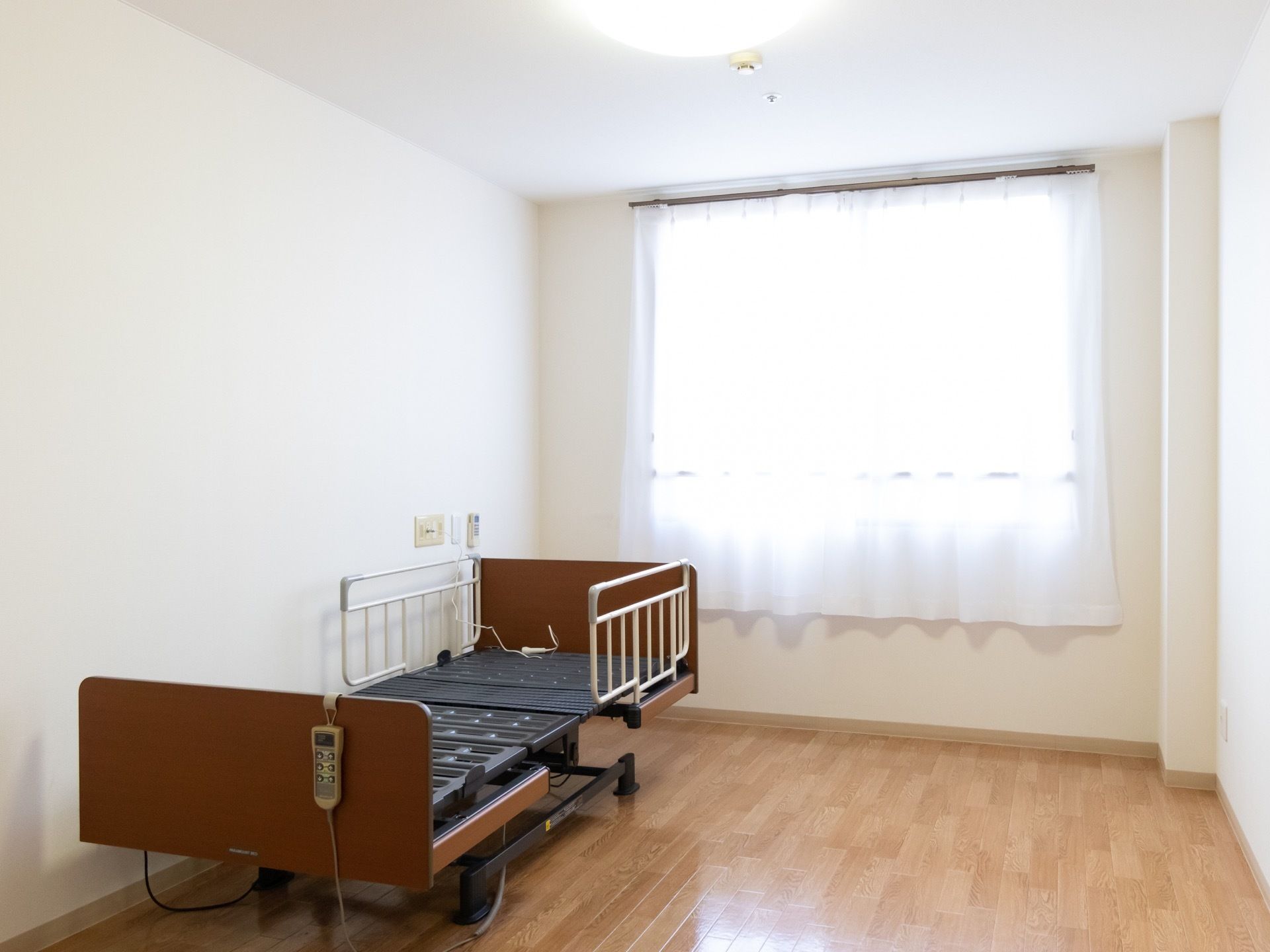 大きな窓がある居室。壁際にベッドが設置されている。入居者様自身で好みの高さや角度に、リモコン1つで簡単に調整ができる。