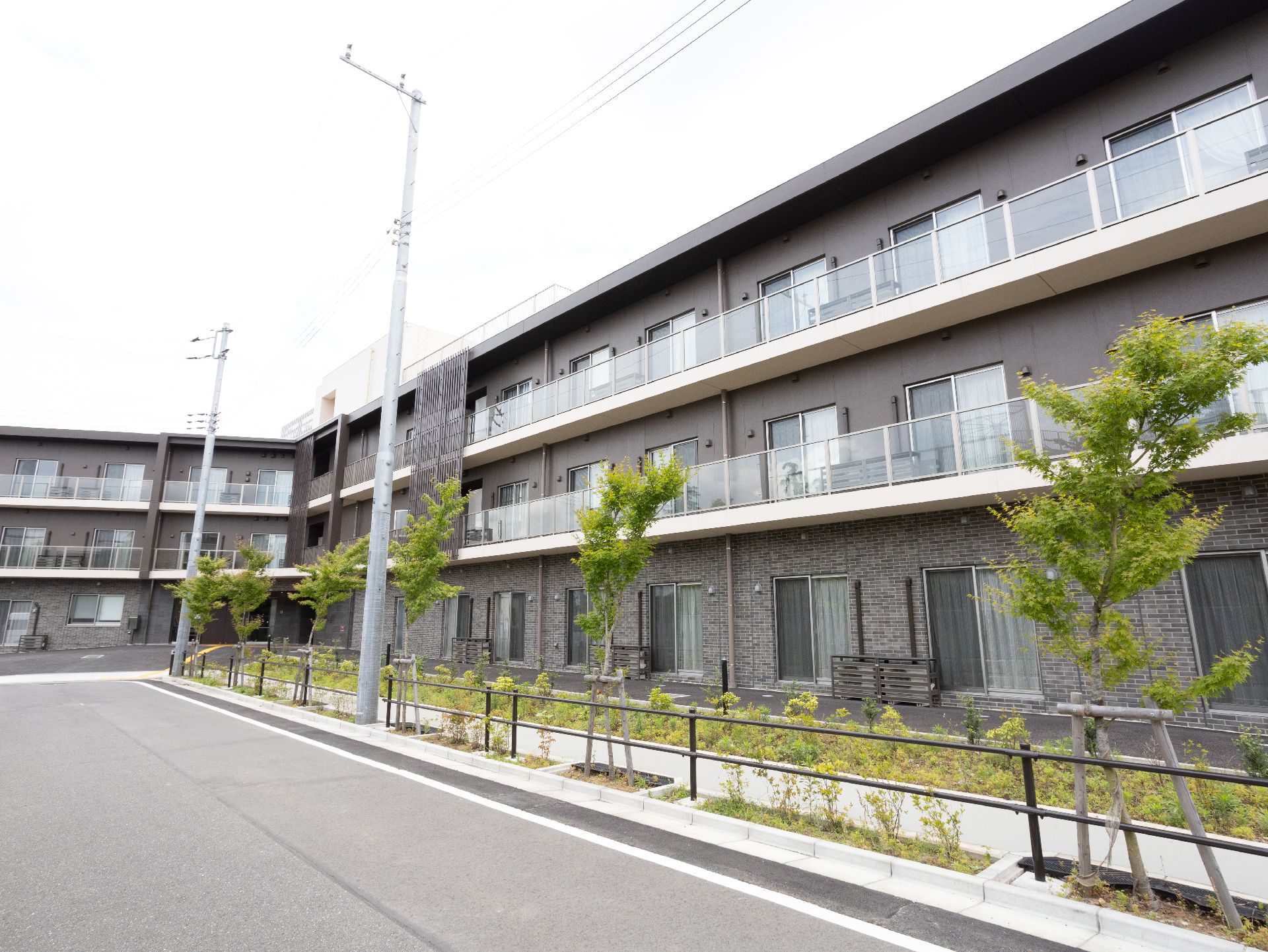 落ち着いた色合いの建物で、敷地内にある庭木の緑が美しい施設の外観