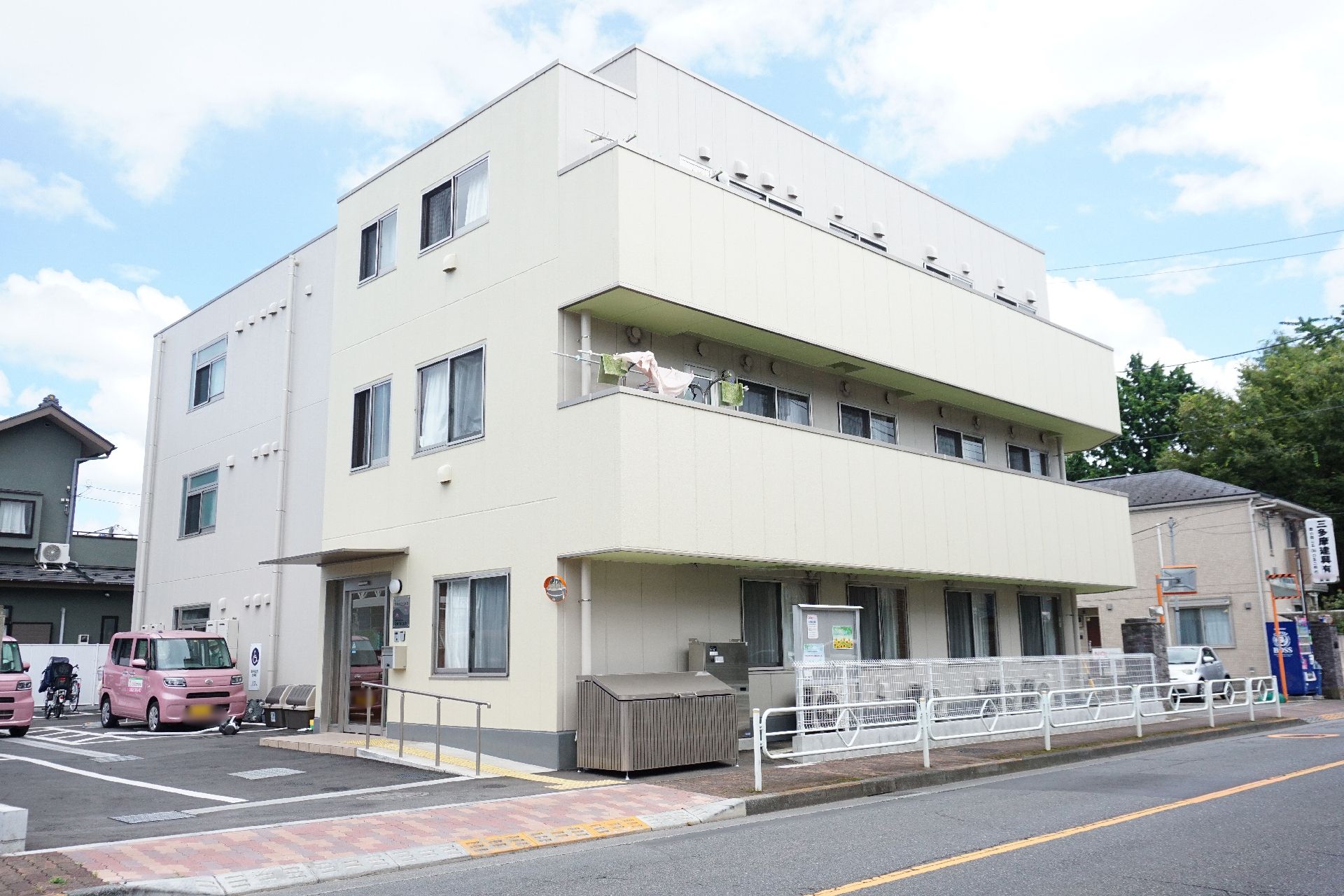 白い外壁で、居室からベランダに出られることがわかる施設の外観