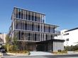 5階建ての建物は壁面がガラス窓となっている近代的なデザイン。建物の周辺には緑もたくさん植えられている。