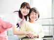 車椅子に座った笑顔の高齢女性と寄り添う女性ヘルパー