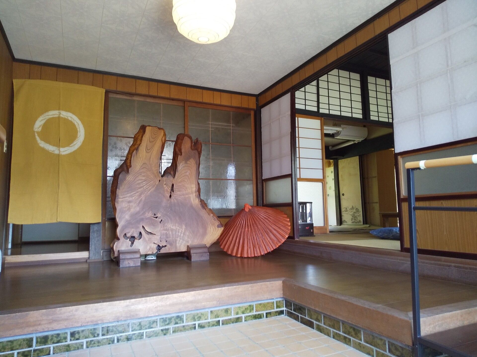 和のテイストを基調とした旅館のような内観。玄関には和傘や木の間仕切りが置かれている