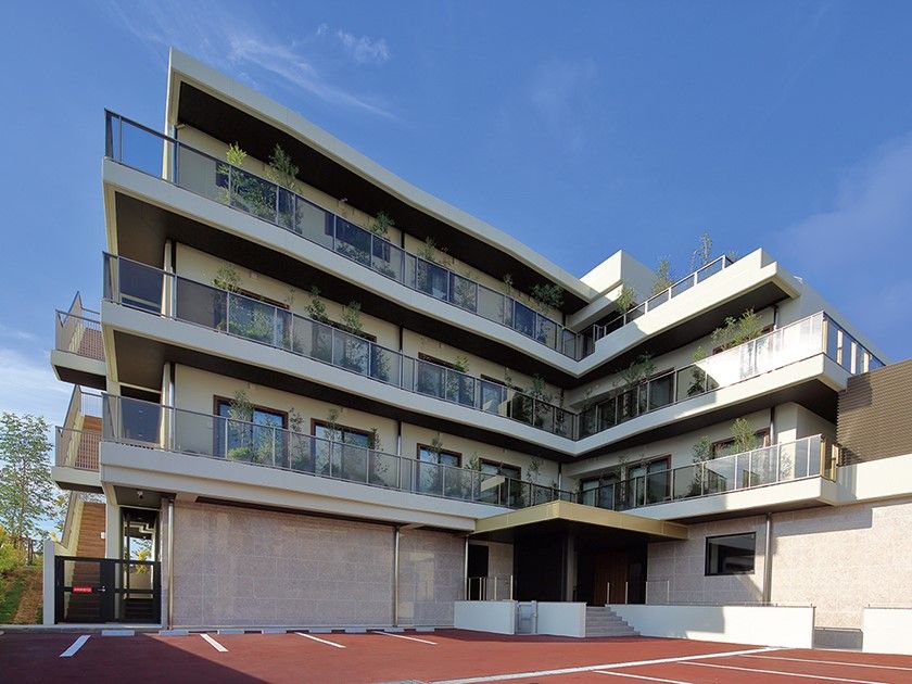 白を基調とした4階建ての建物の各フロアにベランダがあり、敷地内には駐車場がある。